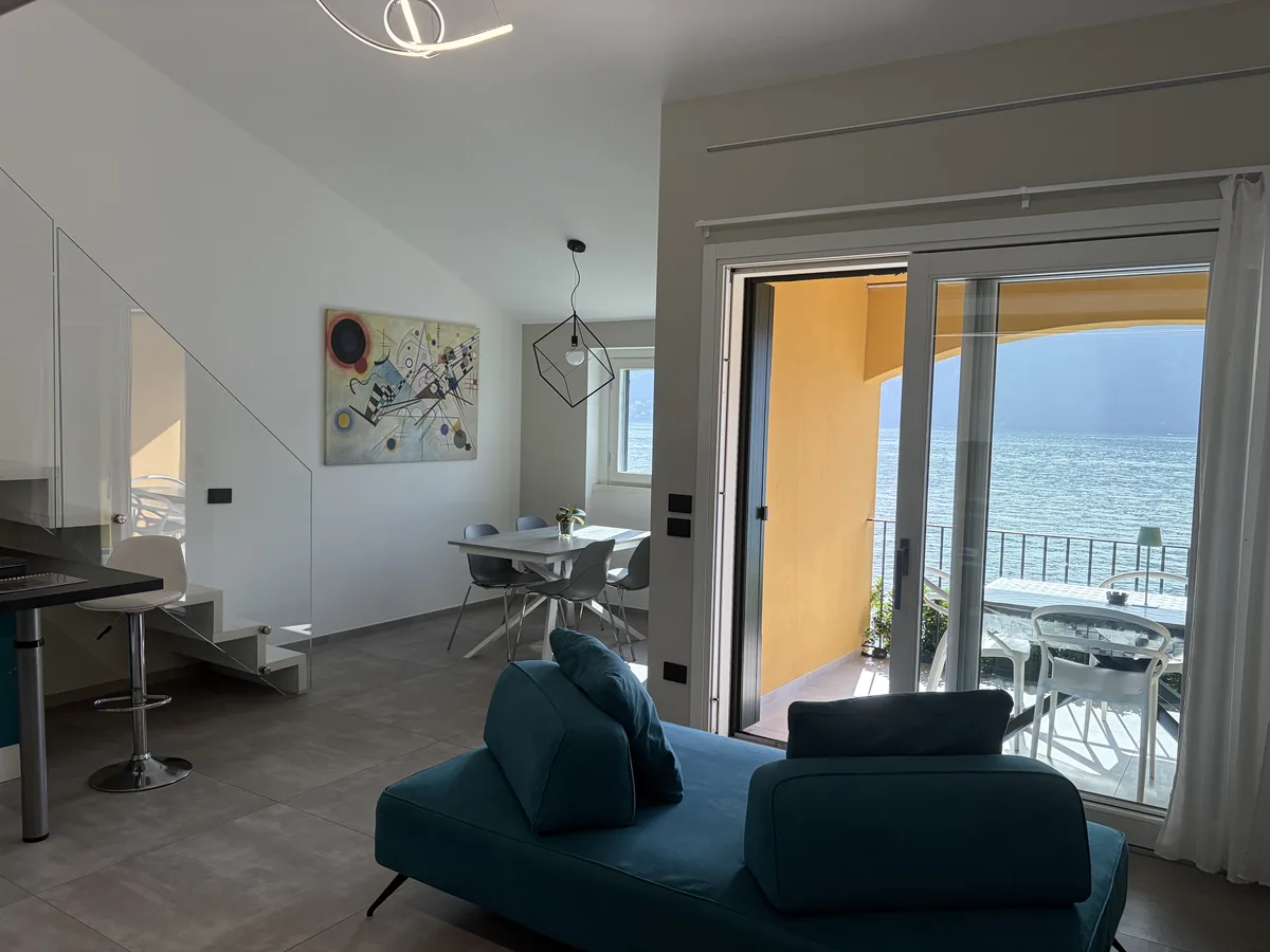 Il soggiorno con la portafinestra aperta sul balcone e sul lago